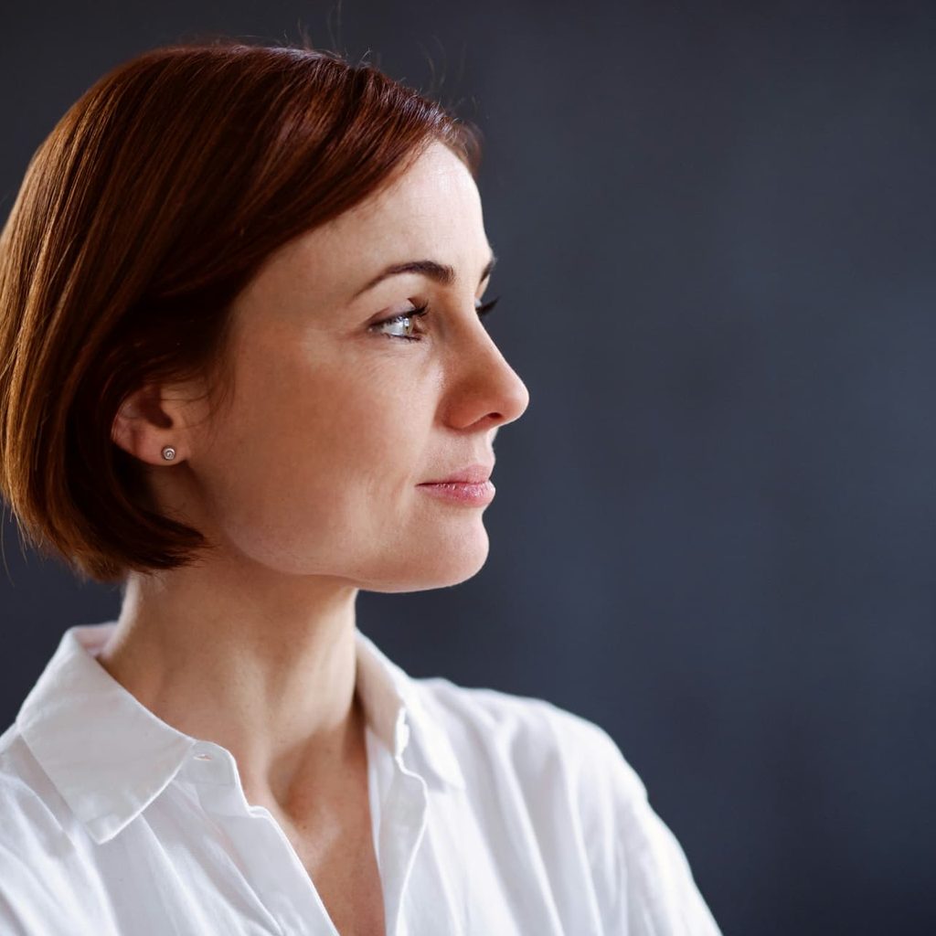 Profile portrait of a woman in a white shirt against a dark backdrop