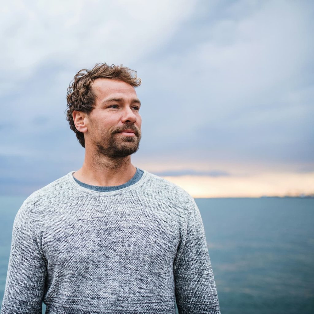 Man in his thirties looking out over the sea at dusk